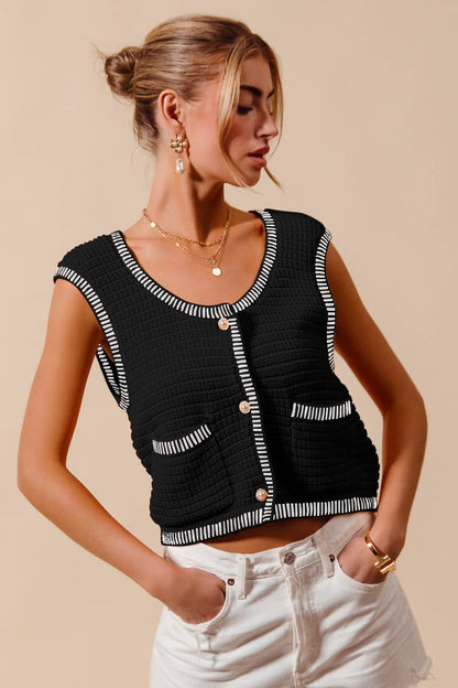 Black vest for women sweater with white trim and buttons worn with white shorts by a woman