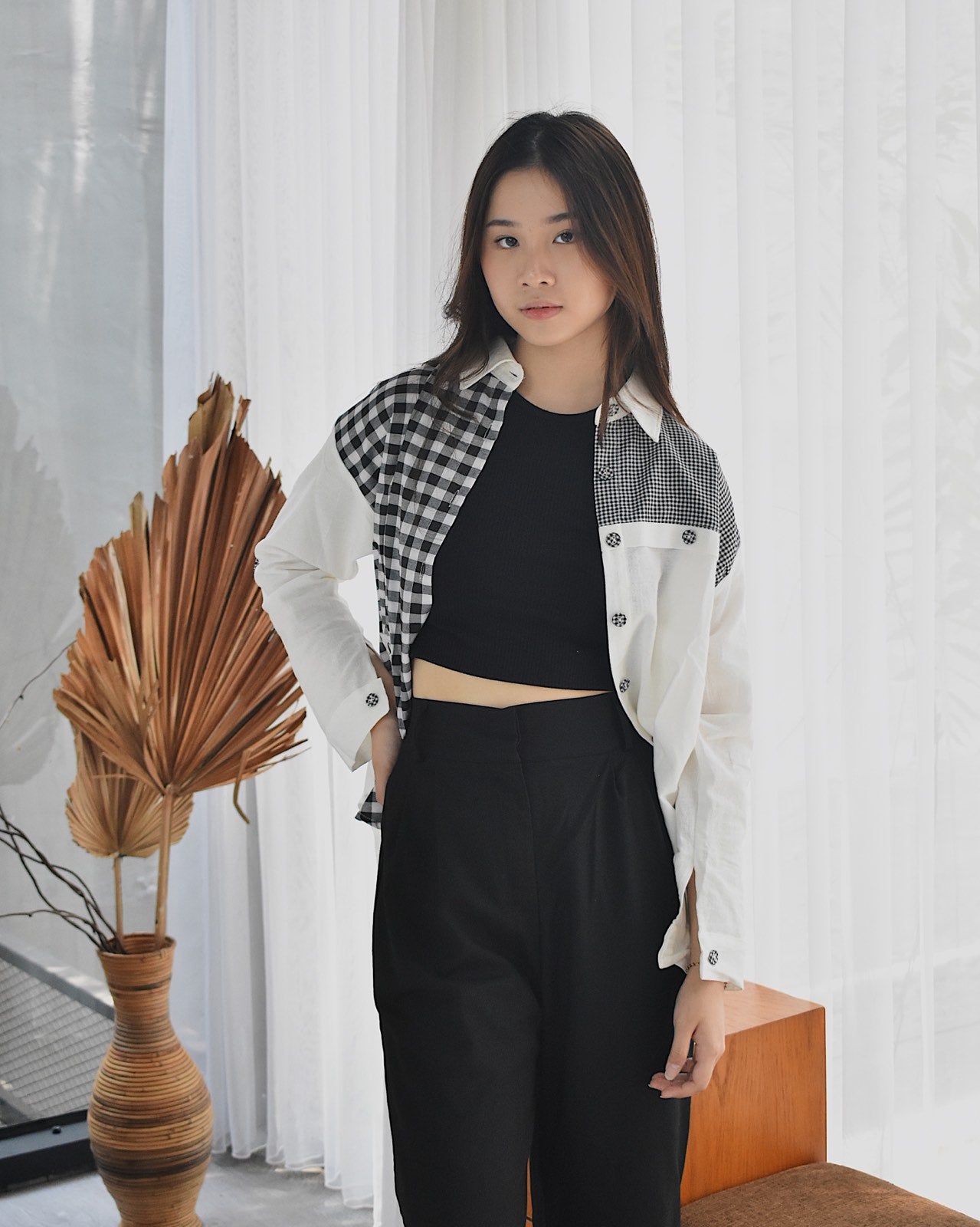 Young woman wearing an affordable women's fashion shirt with black and white checkered pattern and white sleeves