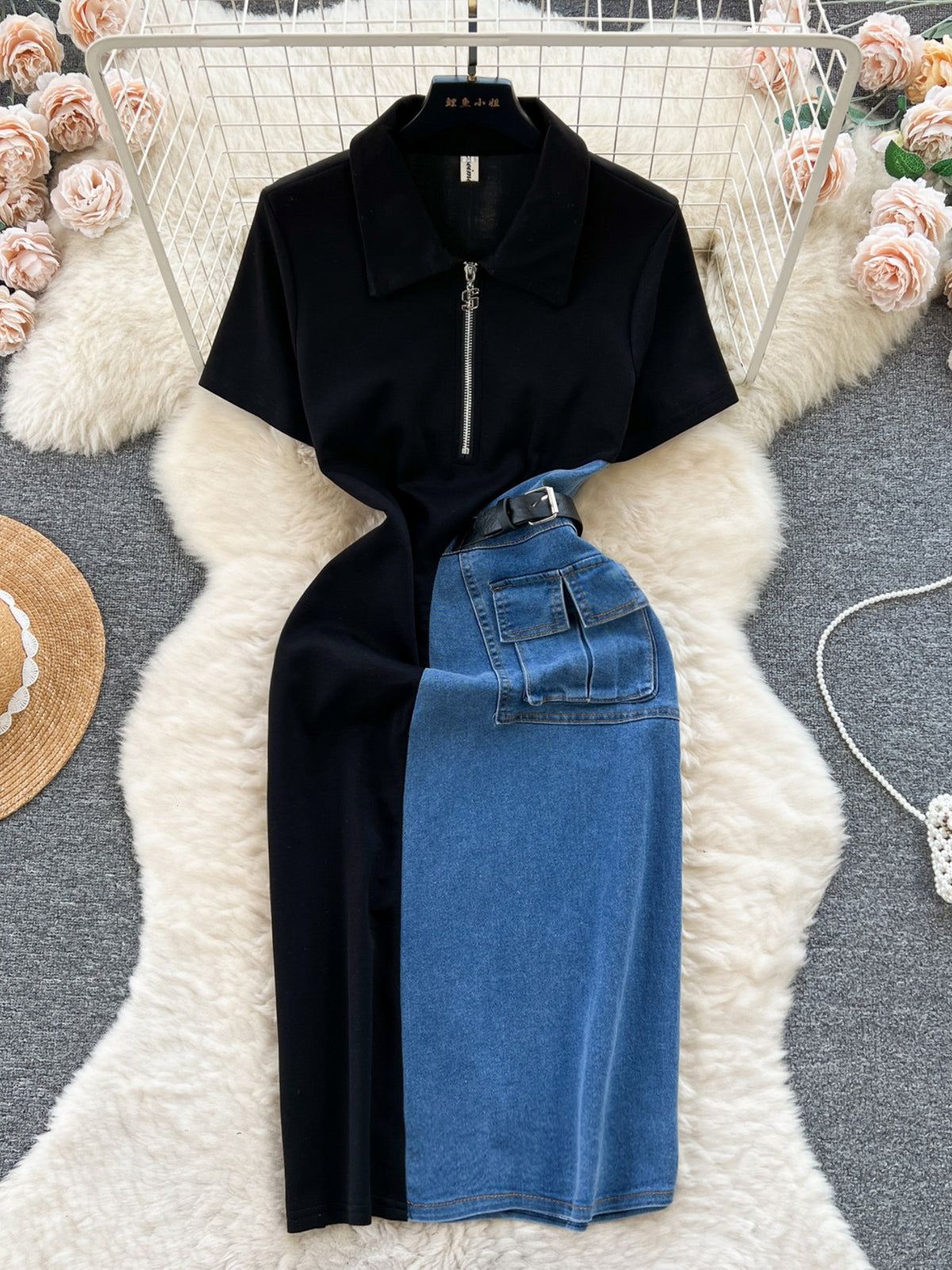 Dress in denim and black fabric with half zipper and belt detail laid flat on white rug